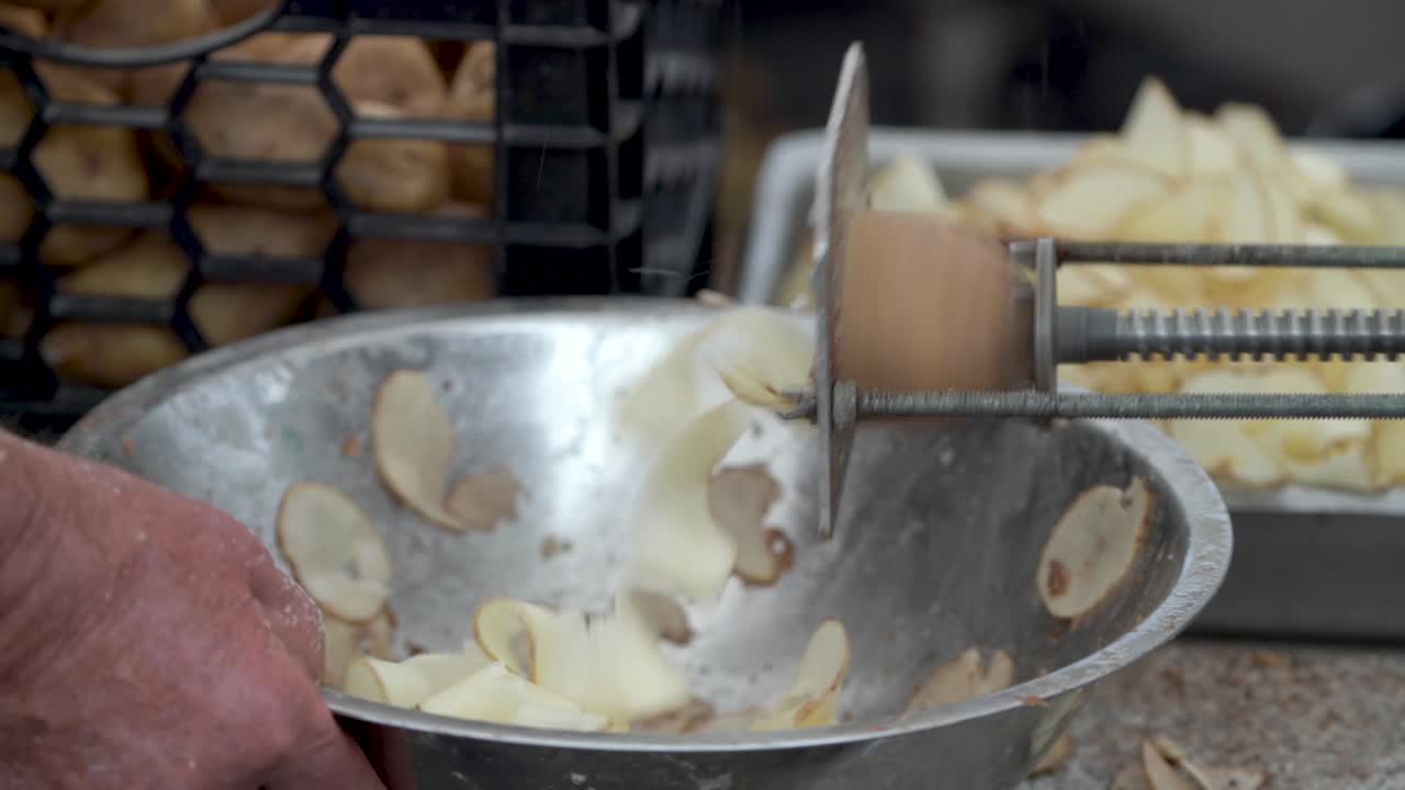 Closeup of a potato going into a tornado potato cutter churning out curly fries