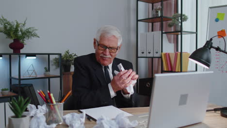 senior business office man use laptop throwing crumpled paper, having nervous breakdown at work