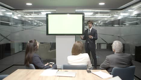 Confident-speaker-talking-with-coworkers-and-pointing-at-display