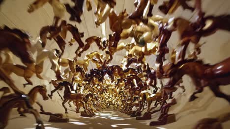 numerous horse figurines gallop in a dynamic art installation, forming a captivating tunnel that showcases the beauty of movement and the artistry of kinetic sculpture