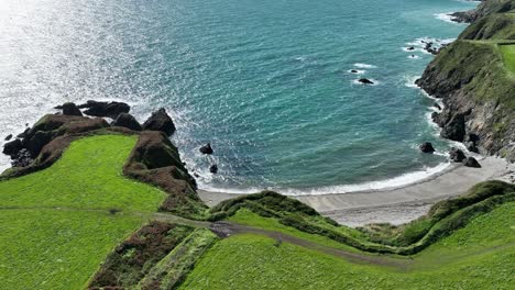 Costa-De-Cobre-Waterford-Irlanda-Toma-Estática-De-Una-Playa-Secreta-Con-Acantilados-Y-Un-Mar-Brillante-En-Un-Día-De-Verano