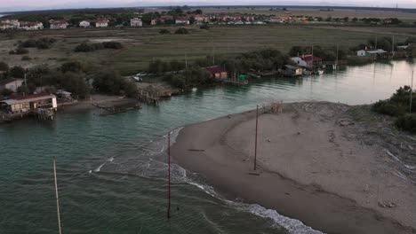 Aerial-shot-of-the-valleys-near-Ravenna-where-the-river-flows-into-the-sea-with-the-typical-fishermen's-huts-at-sunset