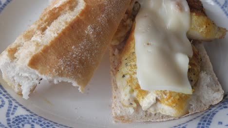 Bocadillo sandwich with grilled chicken and melted cheese, close-up shot