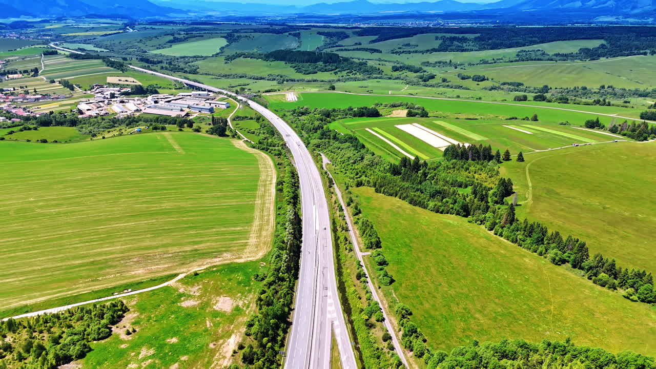Road passes the meadows in the countryside of Slovakia. Rural area at backdrop. Aerial view