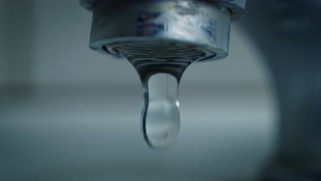 a close-up view of a faucet shows water dripping steadily into a sink, creating a soothing sound. bright daylight illuminates the scene, highlighting the water's clarity and motion.