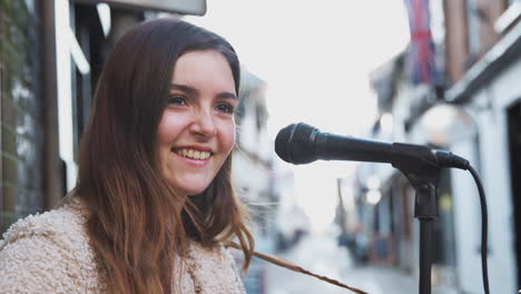 retrato de una músico femenina tocando la guitarra acústica al aire libre en la calle