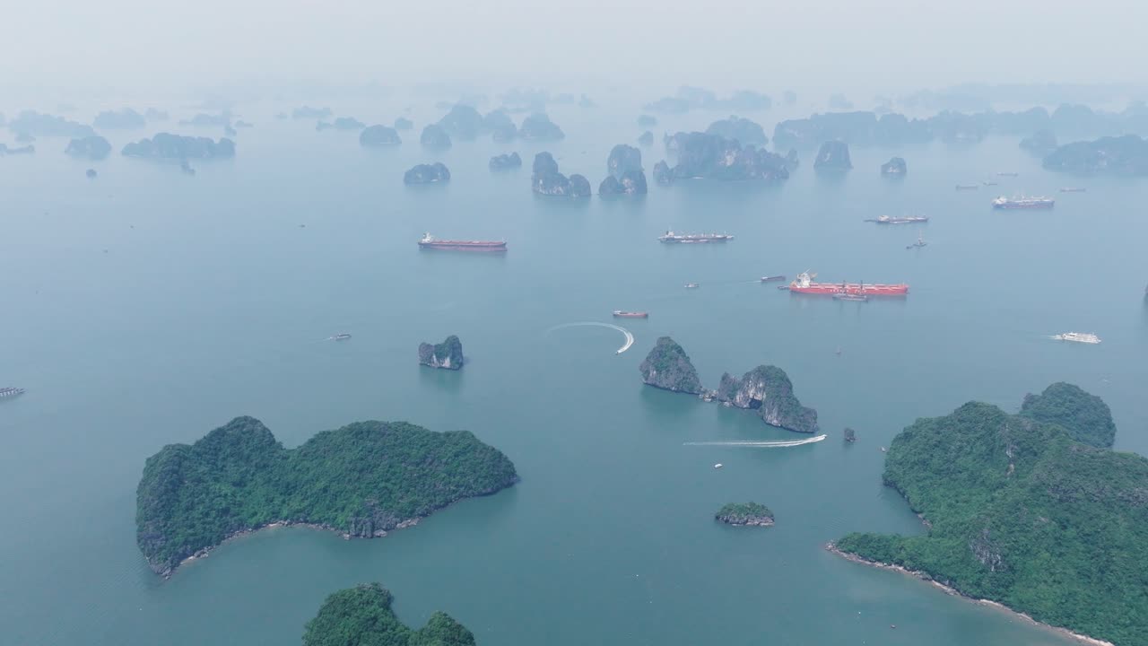 Boats and limestone islands in foggy Ha Long Bay, calm and dreamy atmosphere