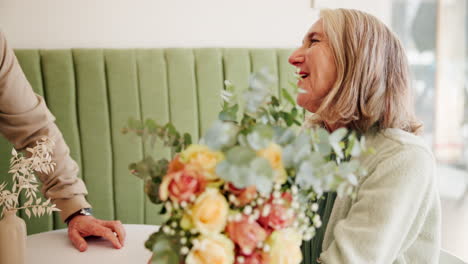 elderly couple celebrating with flowers in a cafe