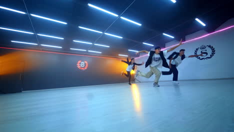 three male dancers showing a dance in the spacious studio. boys band dancing hip hop. low angle view.