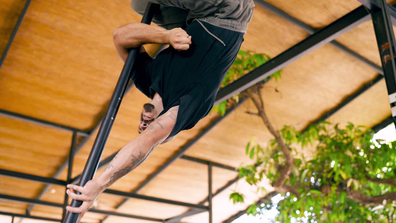 Man Performing Pole Acrobatics Upside Down in Outdoor Studio