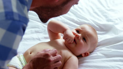 padre jugando con su bebé acostado en una cama