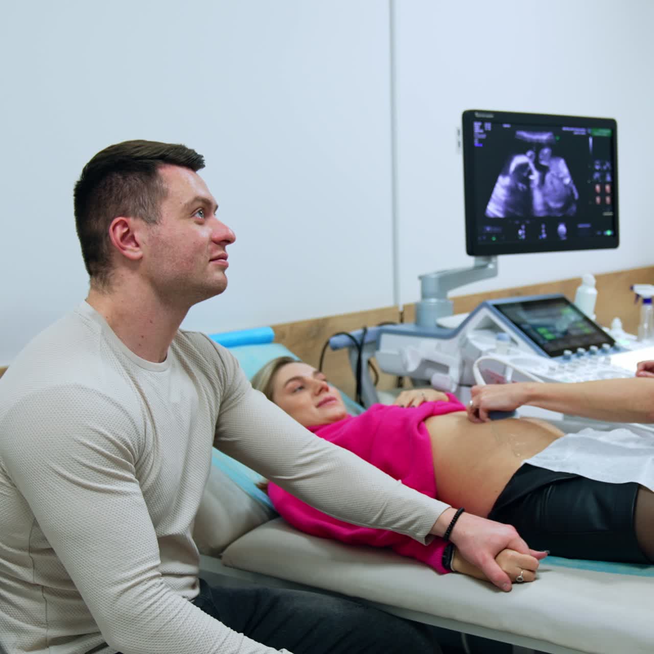 Caucasian woman and her husband at the doctor's check up. Obstetrician examine pregnant lady on ultrasound equipment