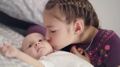 Schönes-Mädchen,-Das-Baby-Küsst,-Das-Auf-Sofa-Liegt.-Schwester-Küsst-Neugeborenen-Bruder