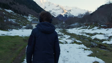 Person Hiking in Snowy Mountains with Headphones