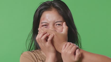 얼굴에 이 있는 젊은 아시아 여성의 폭력 피해자, 그녀의 입에 남자의 손에 의해 학대, 스튜디오의 녹색 스크린 배경