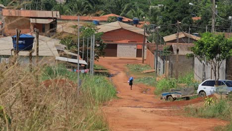 mujer camina descalza por un camino de tierra en un barrio empobrecido en las zonas rurales de brasil