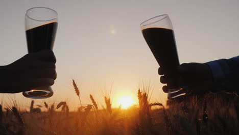 manos con botellas de cerveza chocan contra el fondo de un campo de trigo 3