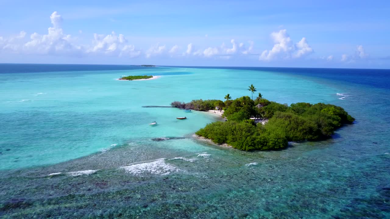 몰디브의 밝은 하늘 배경에 잔잔한 청록색 라군으로 씻겨진 거대한 산호초 장벽 가장자리에 무성한 초목이 있는 천국 열대 섬