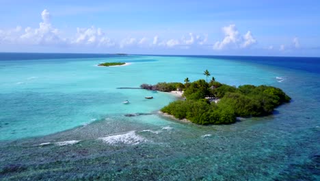 Paradiesische-Tropische-Insel-Mit-üppiger-Vegetation-Am-Rande-Der-Großen-Korallenriffbarriere,-Umspült-Von-Einer-Ruhigen-Türkisfarbenen-Lagune-Auf-Einem-Hellen-Himmelshintergrund-Auf-Den-Malediven