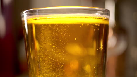 close up of craft beer being poured in to a pint glass, light background