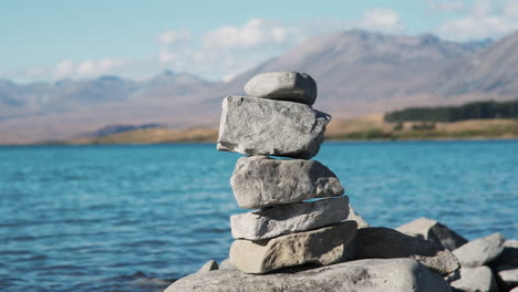 rock cairn against the backdrop of beautiful blue water and majestic mountains