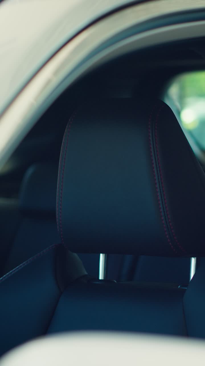 Primo piano del poggiatesta in pelle nera di un sedile auto con cuciture rosse