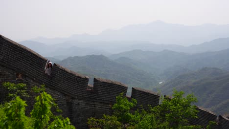 tourist waving from the great wall of china at jinshanling, a scenic outdoor view