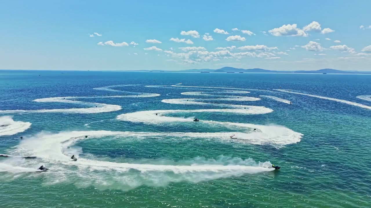 Corrida de jet ski acontece em um dia ensolarado nas águas de uma grande baía, com céus azuis claros e um cenário deslumbrante.