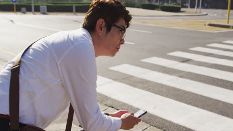 asian man sitting on bicycle using smartphone on the city street