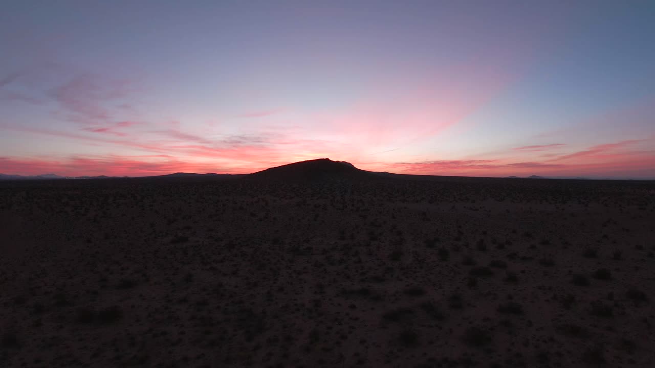 la vista desde la cabina de un jet volando bajo sobre el desierto de mojave hacia una montaña al amanecer