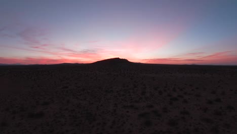 the view from the cockpit of a jet flying low over the mojave desert towards a mountain at sunrise