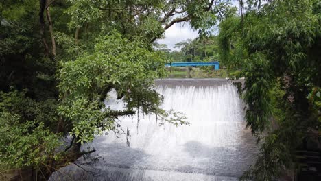 Aerial-:-Air-Terjun-Bandung-waterfall-:-river-water-flowing-down-an-old-historic-dam-in-a-tropical-Jungle-Bali,-Ubud-–-Indonesia