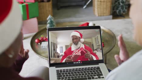 Diverse-senior-female-friends-using-laptop-for-christmas-video-call-with-happy-santa-on-screen