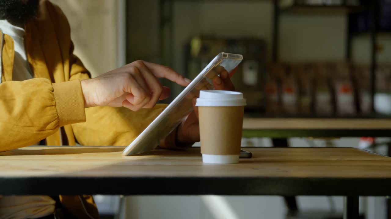 Mezzo busto di uomo multirazziale che usa un tablet digitale in un caffè 4k