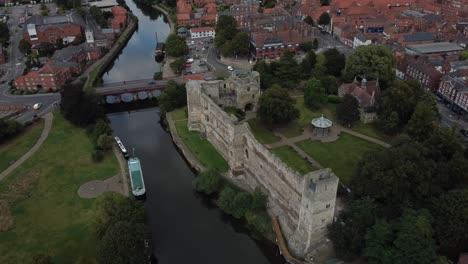 aerial footage rotating around the front of newark castle and gardens. the river trent and surroundings residential buildings can be seen including a road bridge over the river.