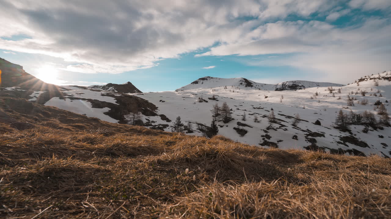 amanecer sobre colinas cubiertas de nieve con cielo azul y nubes dispersas, lente de gran ángulo
