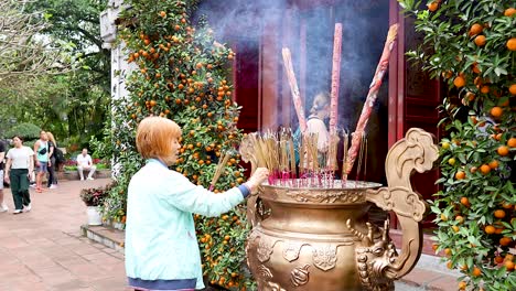 person lighting incense at temple in hanoi