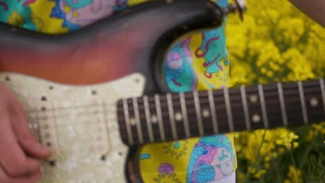 movimiento manual de la cámara siguiendo al guitarrista bailando. un hombre con una camiseta toca la guitarra en un campo de colza.