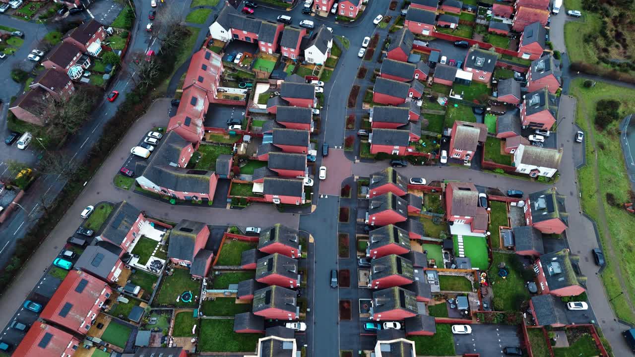 Riprese aeree effettuate con drone che sorvola un quartiere residenziale inglese nel sud dell'Inghilterra durante l'ora blu al tramonto. Strade trafficate e atmosfera tranquilla con giardini, alberi e un laghetto