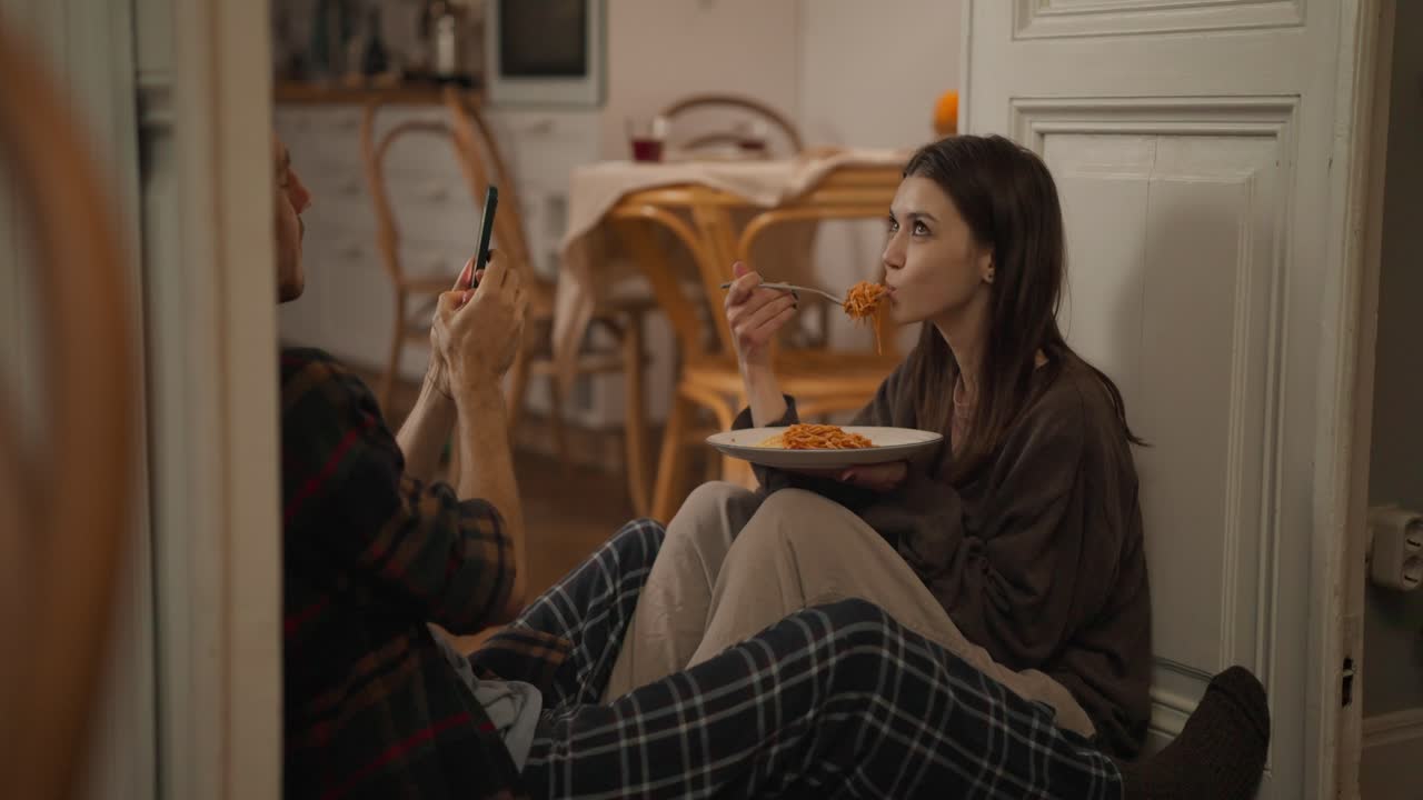 Couple taking pictures of spaghetti indoors