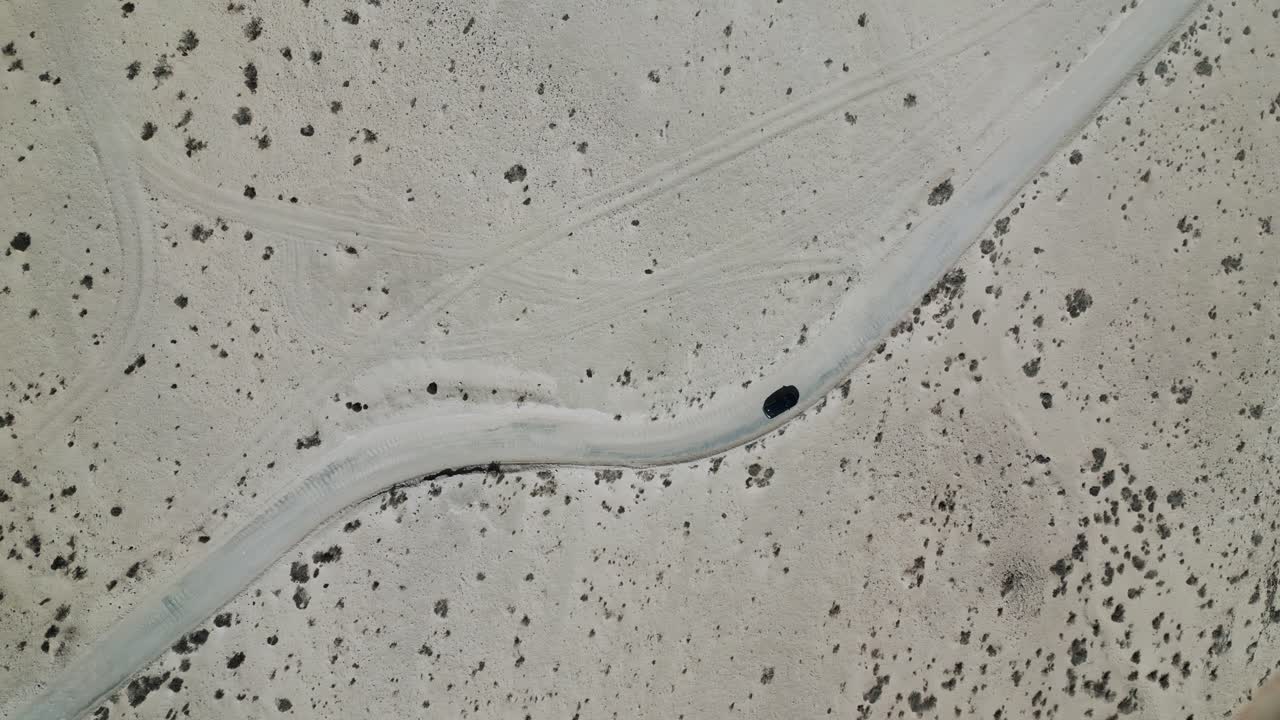 Drone footage of a car driving across the arid desert landscape of Fuerteventura. Perfect for themes of travel, adventure, freedom, and exploration.