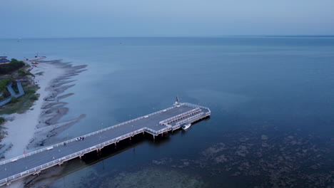 Wenige-Menschen-Gehen-Auf-Dem-Molo-Pier-Des-Polnischen-Dorfes-Jastarnia-In-Der-Ostsee-Spazieren-–-Luftaufnahme-Bei-Sonnenuntergang