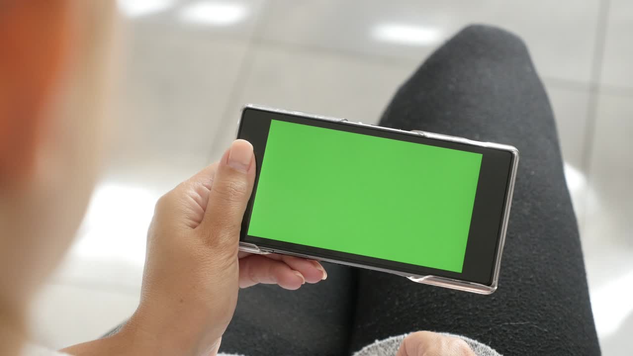pantalla de teléfono móvil con pantalla verde en manos de mujer rubia