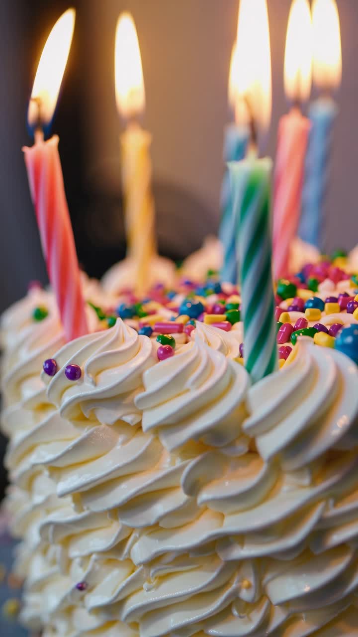 Close-up video angle of a colorful birthday cake with lit candles, showcasing intricate frosting