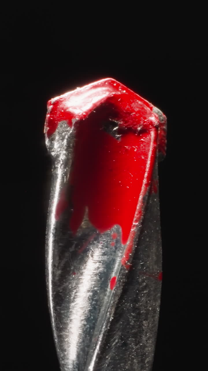 Pobedite tip as cobalt alloy of concrete drill stained with red paint at bright studio light. Professional instrument for making holes on black background macro