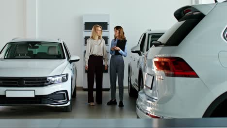 mujeres discutiendo la compra de automóviles en la sala de exposiciones