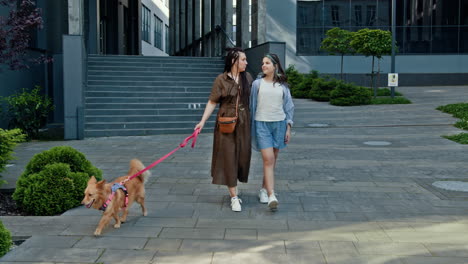 mother and daughter walking a dog in the city