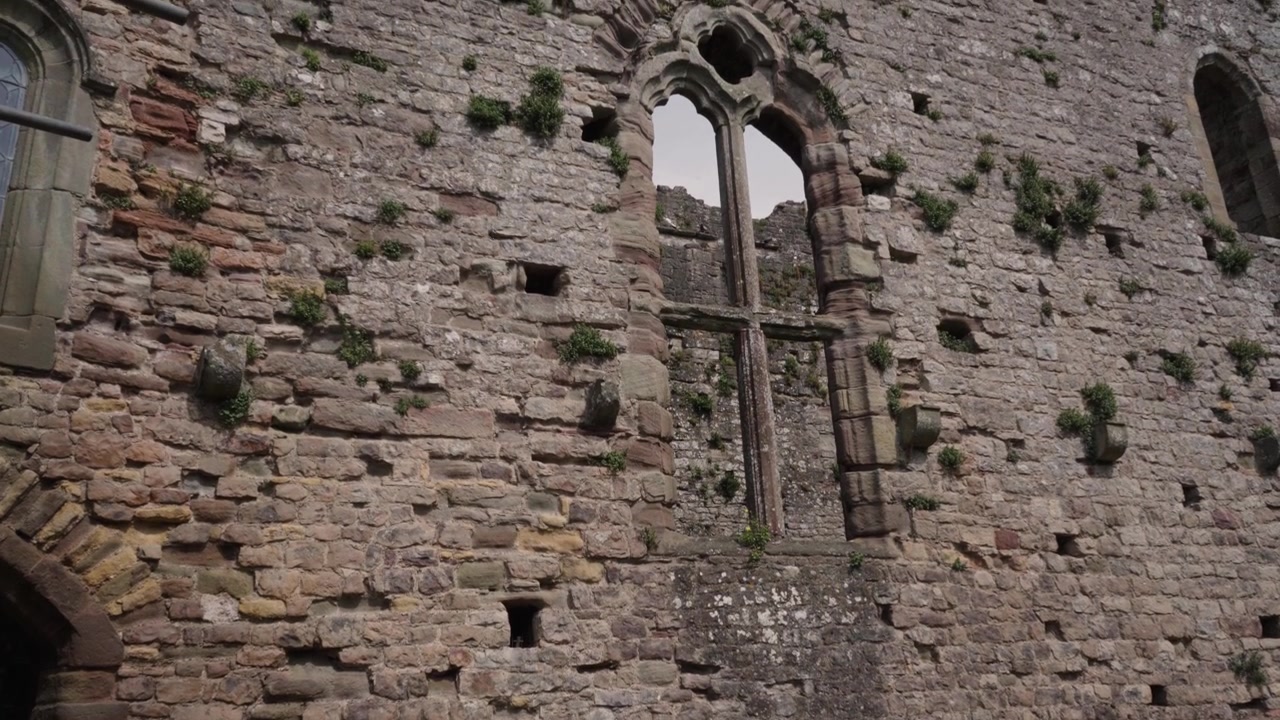 Castelo de Chepstow exibindo suas muralhas antigas, torres e localização à beira do rio. A iluminação natural e o enquadramento estável criam uma cena atemporal e visualmente atraente