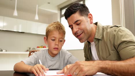 hijo dibujando con su padre en la mesa