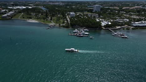 aerial drone footage over the loxahatchee river with boats moored at the piers and a boat passing by in florida